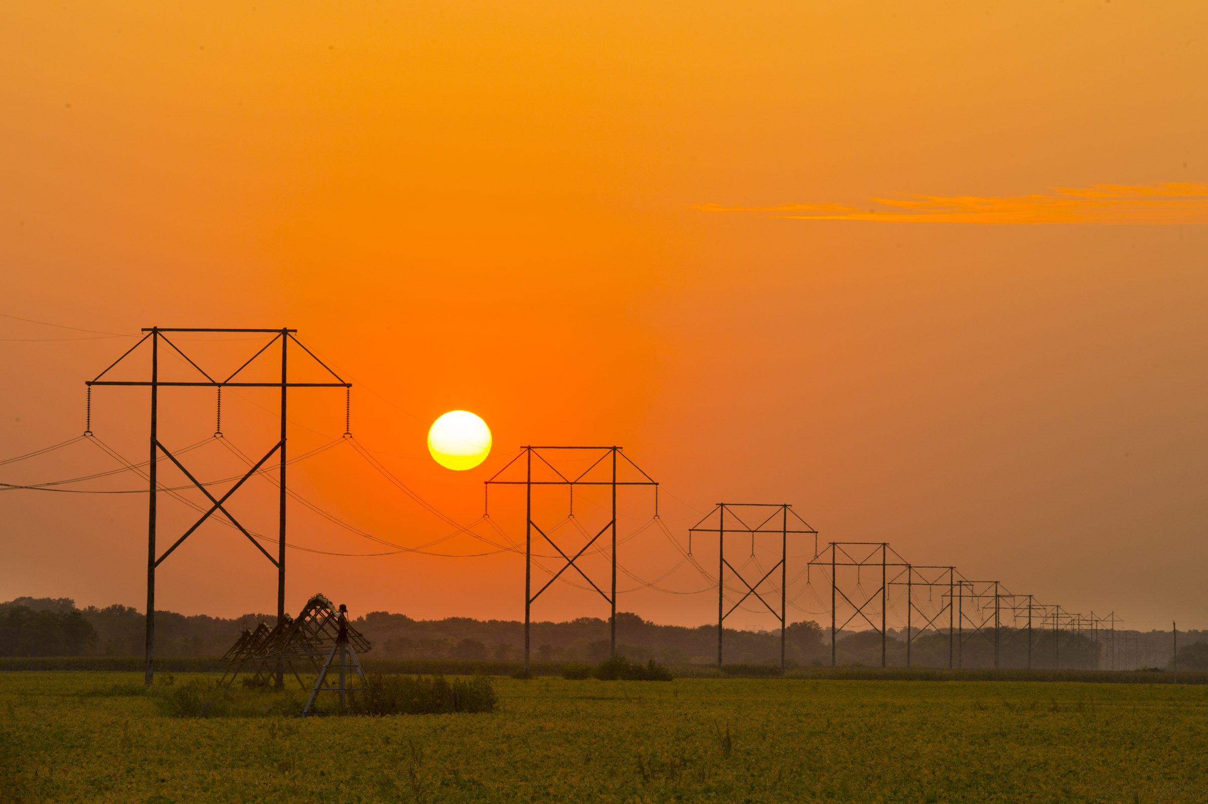 Transmission lines crossing Iowa farmland at sunset